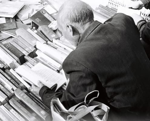 Bureau ou salle de réunion feutrée, lumière naturelle froide, ambiance alpine ou helvétique implicite. Un dirigeant en costume sobre concentré sur des documents financiers ou une analyse, sans sourire commercial.