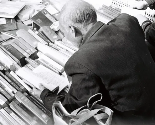 Bureau ou salle de réunion feutrée, lumière naturelle froide, ambiance alpine ou helvétique implicite. Un dirigeant en costume sobre concentré sur des documents financiers ou une analyse, sans sourire commercial.